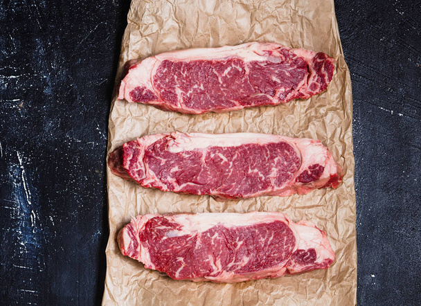 Trois steaks de bœuf marbré frais sur un papier
  - Photo, image