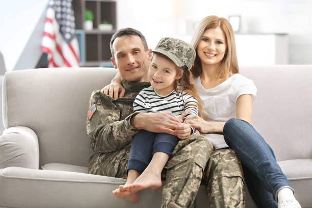 Soldier in camouflage and his family sitting on sofa at home - Foto, imagen