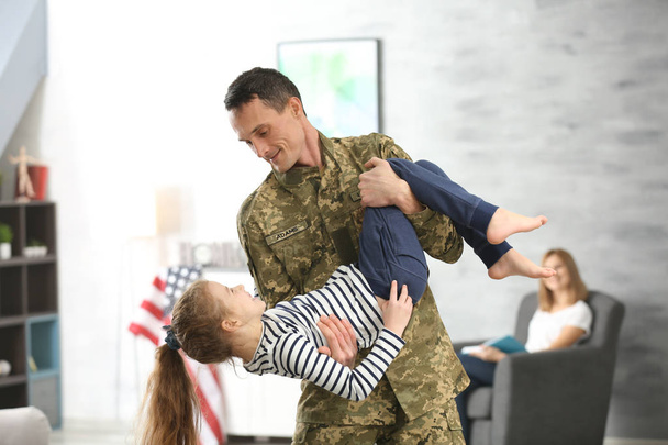 Soldado en camuflaje jugando con su hija en casa
 - Foto, imagen