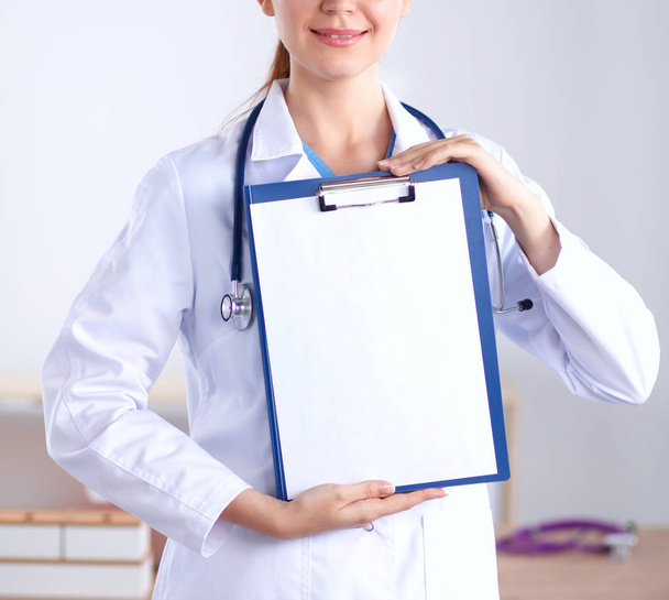 Smiling female doctor with a folder in uniform standing at hospital - Foto, Imagen