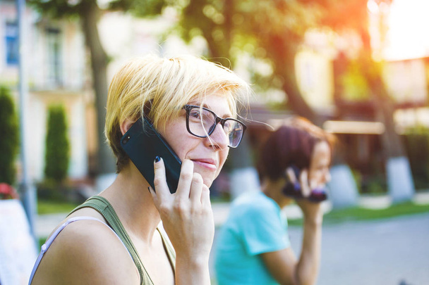 Mladá žena v stylové sluneční brýle, mluvit na mobilním telefonu. - Fotografie, Obrázek