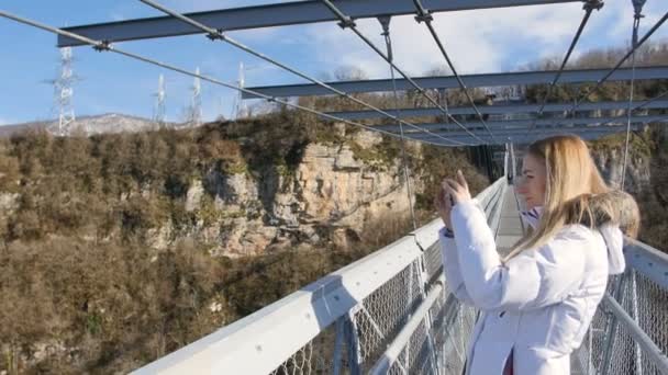 Donna scattare foto del paesaggio vista sulla natura sul ponte sul canyon
 - Filmati, video