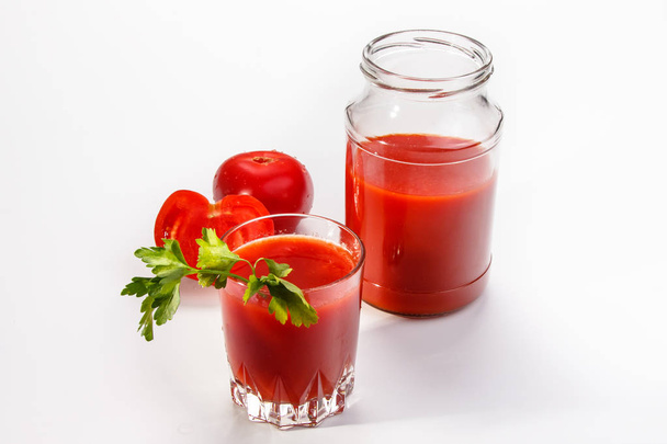 El jugo de tomate se vierte del frasco de vidrio en un vaso
. - Foto, Imagen