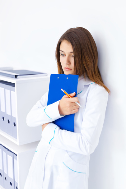 Portrait of pensive young female doctor holding clipboard in hos - Foto, afbeelding