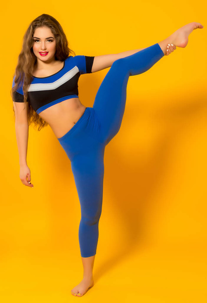 hermosa chica gimnasta en azul ropa deportiva de pie en una pierna
 - Foto, Imagen