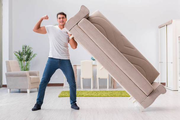 Мужчина передвигает мебель дома
 - Фото, изображение