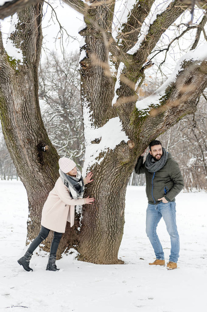 Loving couple enjoying the snow in the park - Foto, afbeelding