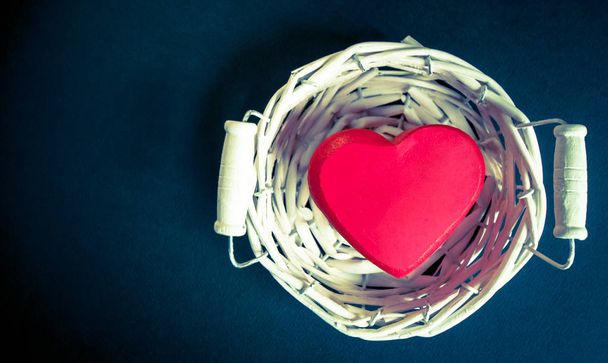red heart in a white wicker basket on a black background - Photo, Image
