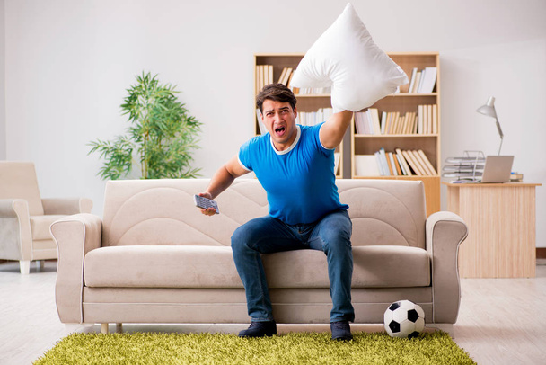 Homme regardant le football à la maison assis dans le canapé - Photo, image