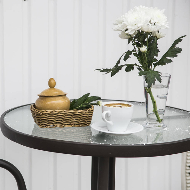 café de la mañana junto a un jarrón de crisantemos en el café terraza de verano
 - Foto, Imagen