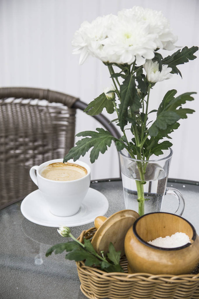 Πρωινός καφές δίπλα σε ένα βάζο με χρυσάνθεμα σε καφέ με καλοκαιρινή βεράντα - Φωτογραφία, εικόνα