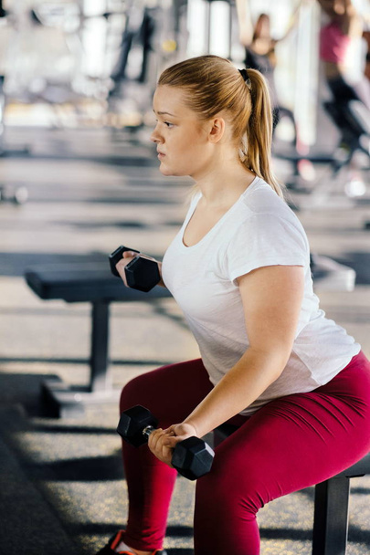 Beginner chubby girl exercising in fitness club - Fotografie, Obrázek