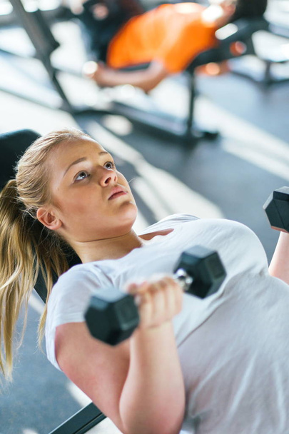 Beginner chubby girl exercising in fitness club - Zdjęcie, obraz