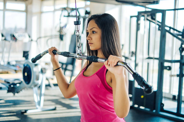 Sports young woman doing exercises in the gym on Lat Machine - Photo, image
