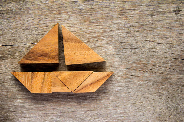 Tangram Raadsel in zeil boot vorm op houten achtergrond - Foto, afbeelding