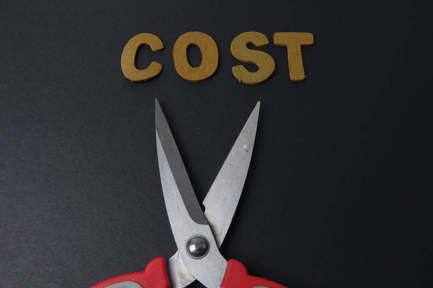 Paire de ciseaux réduit les dépenses d'affaires mot COST pour économiser le coût. Concept d'entreprise et faible luminosité
. - Photo, image