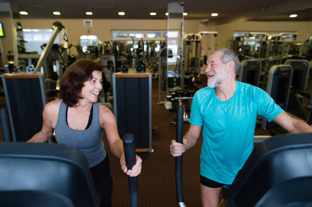 Beautiful fit senior couple in gym doing cardio work out. - Fotoğraf, Görsel