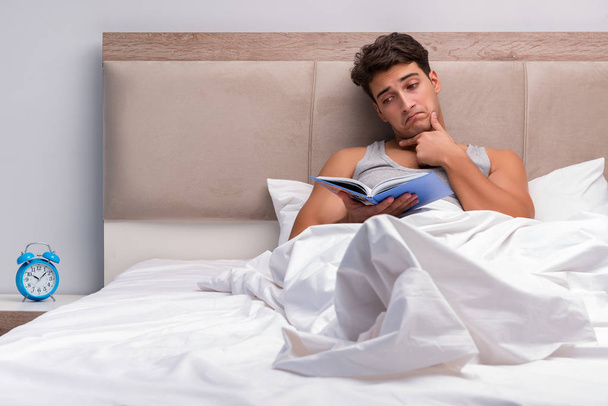 Uomo che legge libro nel letto
 - Foto, immagini