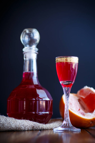 sweet grapefruit alcoholic cordial in the decanter with a glass - Foto, Imagem