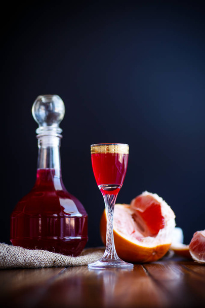 sweet grapefruit alcoholic cordial in the decanter with a glass - Fotó, kép