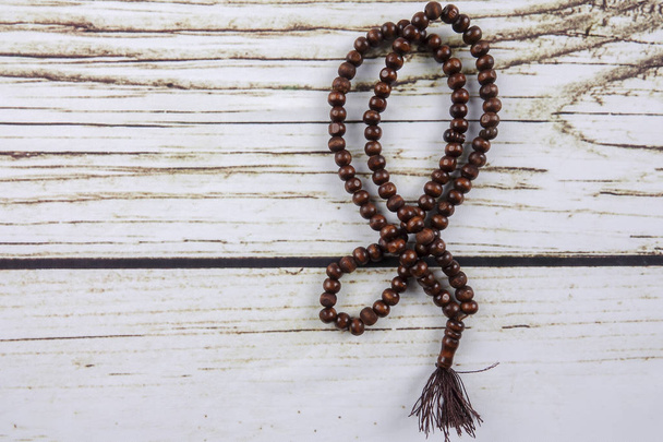 the wooden tasbih or rosary on wooden background. - Photo, Image
