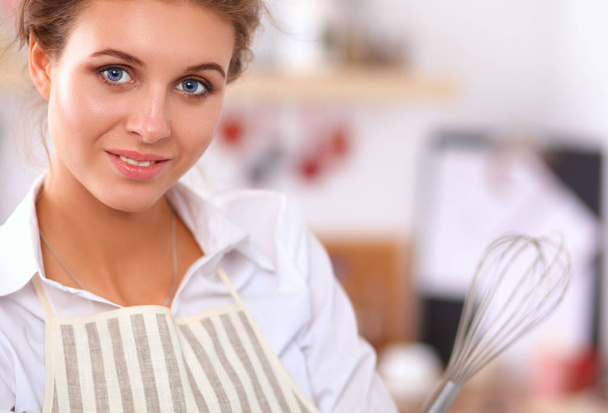 Smiling young woman standing in the kitchen - Foto, Bild