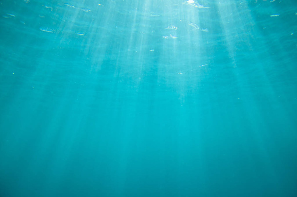 A nap sugarai víz alatti kék háttér - Fotó, kép