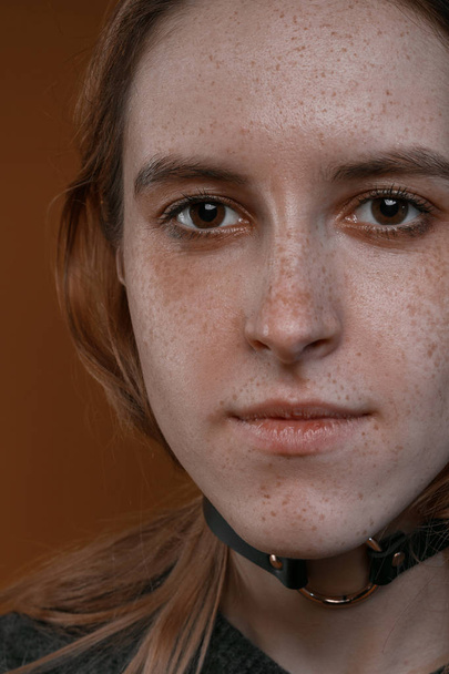 Portrait d'une belle fille avec des taches de rousseur en studio sur un fond brun
 - Photo, image