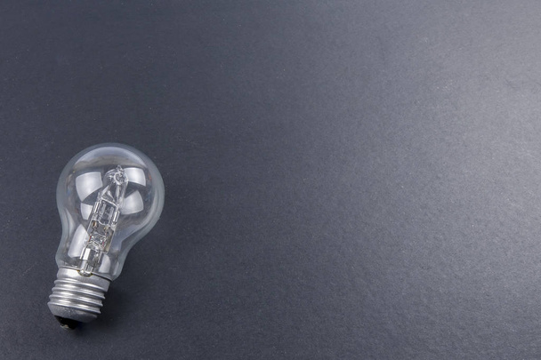 Idee begrip woord idee. Licht van de lamp op een grijze achtergrond. Weinig licht - Foto, afbeelding