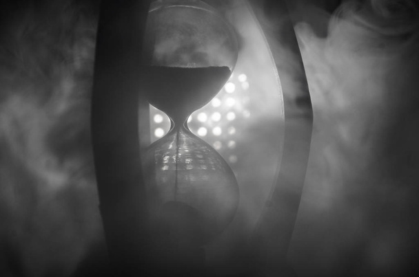 Концепция времени Силуэт песочных часов и дыма на темном фоне с горячим желтым оранжево-синим холодным задним освещением, или символы времени с копировальным пространством, песочными стеклами или песчаными часами
 - Фото, изображение