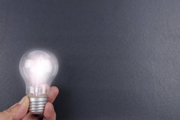Ідея концепції слова IDEA. Світло лампочки на сірому фоні. Низьке світло
 - Фото, зображення