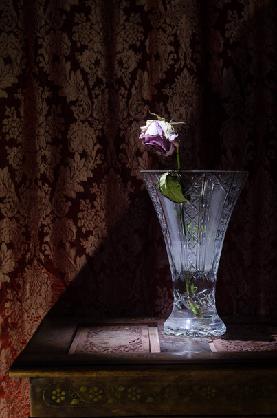 Een verwelken roos betekent verloren liefde, echtscheiding of een slechte relatie, dode roos in een vaas op houten case donkere achtergrond - Foto, afbeelding