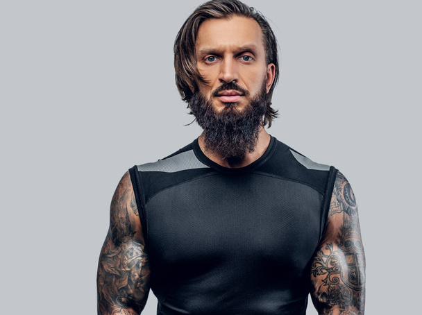 Urheilullinen parrakas mies, jolla on tatuoitu runko
 - Valokuva, kuva