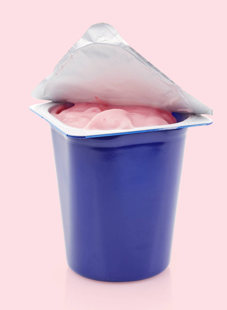 verse roze bessen yoghurt in blauwe plastic pot - Foto, afbeelding