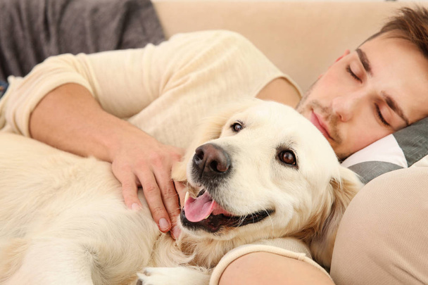 man with dog sleeping on sofa - Zdjęcie, obraz