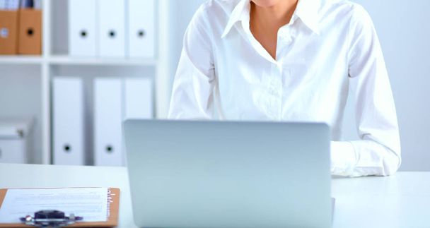 Young woman sitting at office table with laptop - Foto, imagen