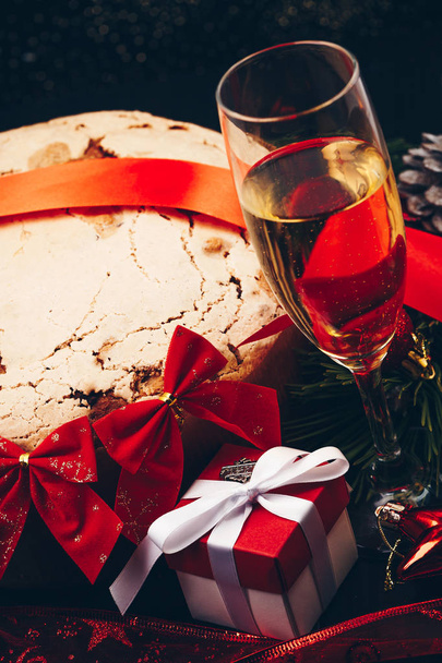 Noël ou Nouvel An. Champagne dans des verres avec des bougies, panettone et cadeau avec arc en satin rouge. Espace de copie. Concept festif
 - Photo, image