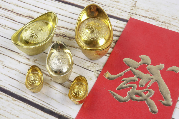 Lingotes de ouro e pacote de dinheiro vermelho para o ano novo chinês festivo em fundo de madeira. Personagem chinês significa sorte, riqueza e prosperidade como visto na imagem
. - Foto, Imagem