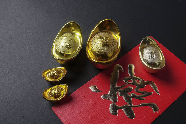 Gold harkot ja punaista rahaa paketti kiinalainen uusivuosi juhla mustalla pohjalla. Kiinalainen luonne tarkoittaa onnea, vaurautta ja vaurautta. Heikko valo
 - Valokuva, kuva