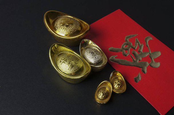 Ράβδοι χρυσού και κόκκινα χρήματα πακέτων για κινεζικό νέο έτος εορταστική σε μαύρο φόντο. Κινέζικος χαρακτήρας σημαίνει τύχη, πλούτο και ευημερία. Συνθήκες χαμηλού φωτισμού - Φωτογραφία, εικόνα