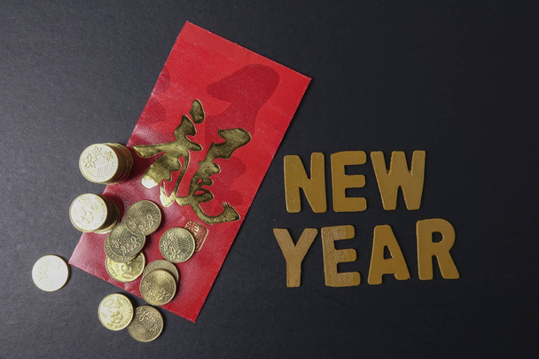 Κινέζικα κόκκινα πακέτο με τα κινεζικά φράση σημαίνει «καλή τύχη και ευημερία», χρυσά νομίσματα και διατύπωση του νέου έτους. Φεστιβάλ κινεζικό νέο έτος. Συνθήκες χαμηλού φωτισμού. - Φωτογραφία, εικόνα