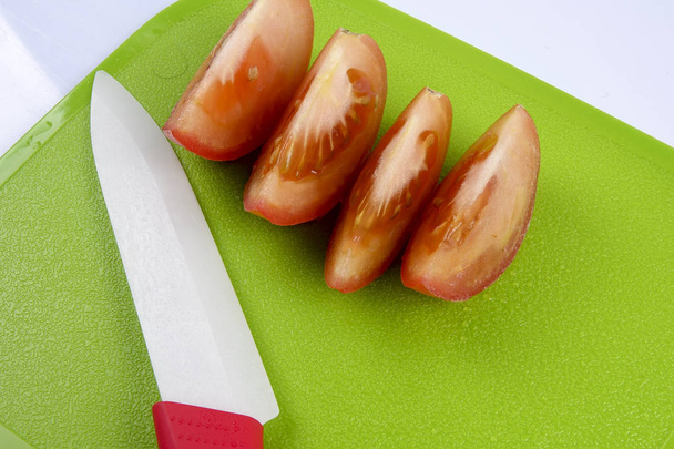 Sliced tomato on green chopping board. - Foto, imagen
