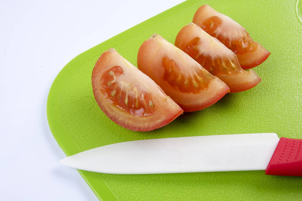 Sliced tomato on green chopping board. - Photo, Image