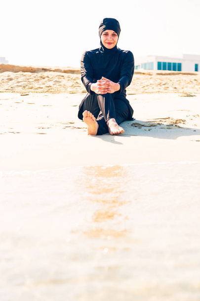Young Woman Wearing Burkini Sitting By The Beach - Fotoğraf, Görsel