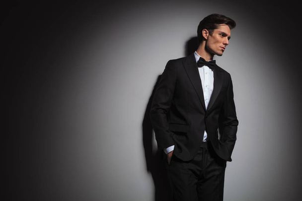 pensive elegant man wearing tuxedo looks away to side  - Φωτογραφία, εικόνα