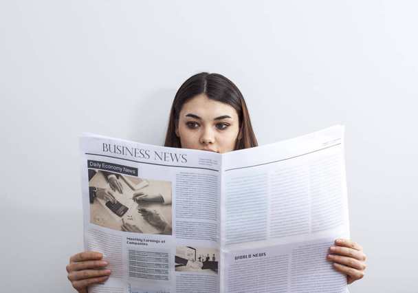 Businesswoman reading newspaper on gray background - Zdjęcie, obraz