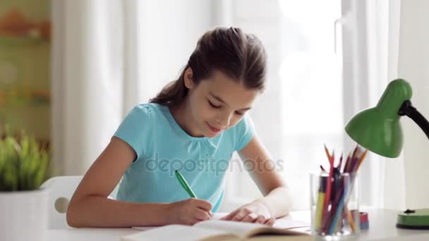 happy girl with book writing to notebook at home - Filmati, video