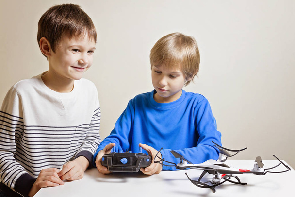 Kids playing with drone at home. One boy holding a radio remote control fo quadcopter. - Foto, Imagem