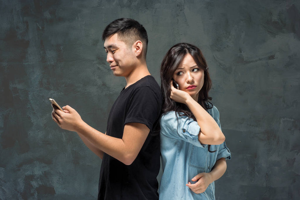 Asian young couple using cellphone, closeup portrait. - Fotó, kép