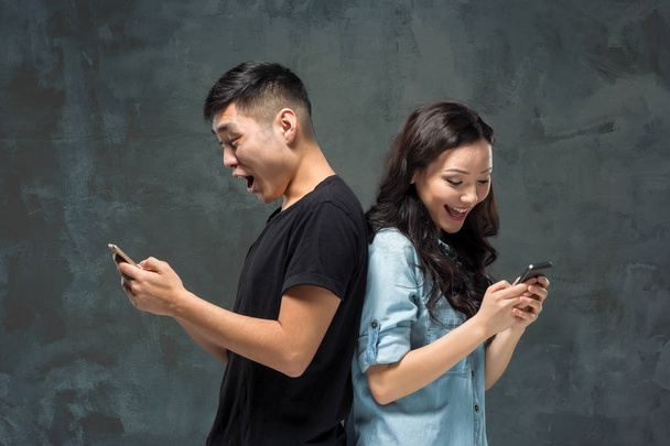 Asian young couple using cellphone, closeup portrait. - Fotó, kép